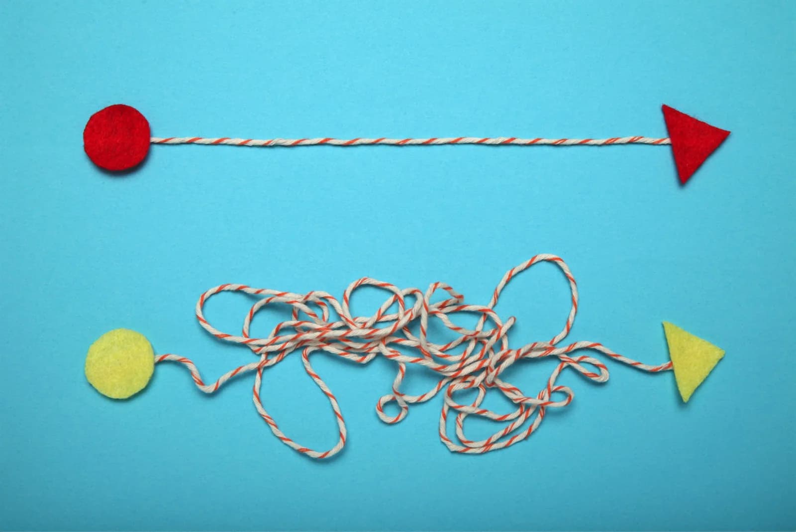 Two craft-material paths on a light blue ground: a red circle connected to a red triangle by a taut straight string, and a yellow circle connected to a yellow triangle by a tangled string that only straightens at the end.